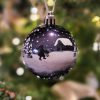 Dark blue shiny christmas bauble with a winter landscape, santas elf and barn
